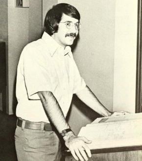 1976年，伯尔·麦奎斯顿拿着参考书站在领奖台上