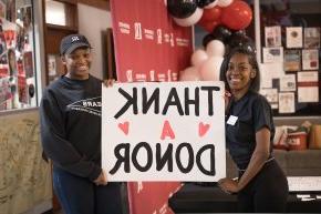 两名女学生举着一张海报，上面写着感谢捐赠者