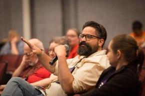 An alumnus with a beard asks a question during the session in Belk Centrum